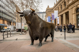 Frankfurt am Main, Germany - November 27, 2015: View of the bronze bull figure right outside the Frankfurt Stock Exchange building, along with people, vehicles, buildings and nature in Frankfurt, Germany